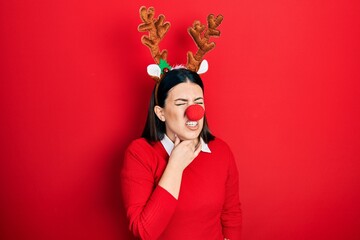 Poster - Young hispanic woman wearing deer christmas hat and red nose touching painful neck, sore throat for flu, clod and infection