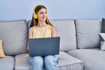 Sticker - Adorable girl using laptop sitting on sofa at home