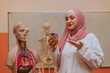 © Malik Nalik - A Muslim female teacher uses the human body model to explain anatomy in biology class in the classroom lab.