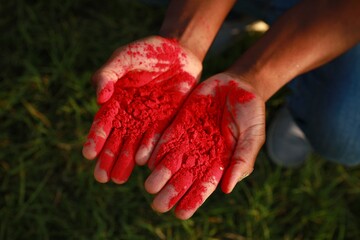 Wall Mural - African American man with red powder dye outdoors, closeup. Holi festival celebration