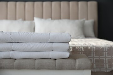 Folded clean blanket on bed bench in room, closeup