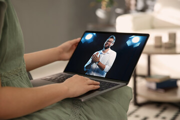 Wall Mural - Woman watching performance of motivational speaker on laptop indoors, closeup