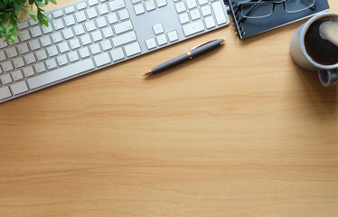 Wall Mural - Top view wooden office desk with notepad, sticky note, eyeglasses, coffee cup and potted plant. Copy space for your text.