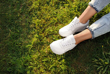 Woman In Jeans And White Shoes Relaxing On Green Grass, Closeup. Space For Text