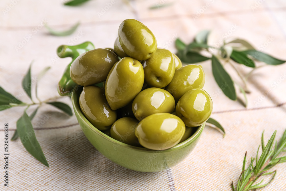 Bowl with tasty canned green olives on table