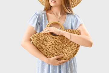 Wall Mural - Young woman with stylish jewelry holding rattan handbag, closeup