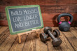 build muscles, live longer and better - inspirational text on a blackboard with dumbbells and kettlebell, fitness and longevity concept