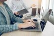 © wutzkoh - Two partnerships developing programming and coding technologies working on laptop and analyzing together.