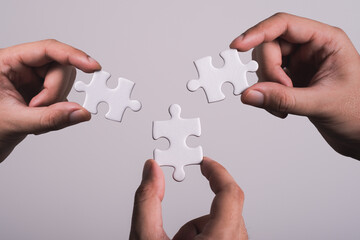 three hands trying to connect couple puzzle piece with gray background. Jigsaw puzzle team work concept. one part of whole. symbol of association and connection. business strategy.