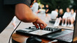 Close-up of an unrecognizable musician beatmaker playing hip hop music on a drum midi controller at an outdoor festival and holding a microphone. Selective focus