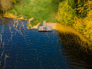 Wall Mural - couple laying on the pier at the lake covered with autumn leaves