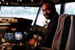 Portrait of happy airliner sitting in airplane cockpit ready to fly, using control panel navigation and dashboard command buttons. Pilot flying aircraft with windscreen compass and radar.