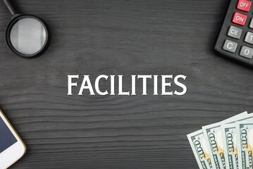 FACILITIES - word (text) and money dollars on the table, phone magnifying glass (loupe) and calculator. Business concept, buying goods and products, paying for services (copy space).