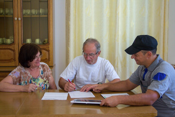 Wall Mural - Image of a handyman plumber presenting a quote for the work to be done to an elderly couple.	