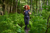 Fototapeta Nowy Jork - Woman hiking on a trail in the forest