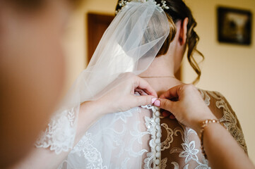 Wall Mural - Bridesmaid helping bride fasten corset and getting her dress, preparing bride in morning for the wedding day.