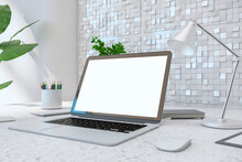 Close Up Of Creative Designer Desktop With Empty White Laptop Screen, Lamp, Supplies Various Other Objects And Shiny Light Tile Wall Background. 3D Rendering.