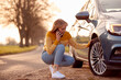 © Monkey Business - Woman Calling For Help On Phone After Car Breakdown On Country Road With Tyre Puncture
