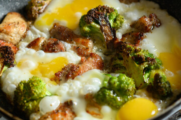 Beef meat, chicken eggs and broccoli vegetables being cooked in a frying pan close-up