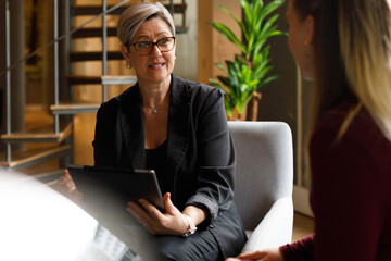 Wall Mural - Businesswoman with tablet explaining to coworker in office