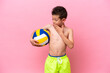 Little caucasian boy playing volleyball isolated on pink background with surprise and shocked facial expression