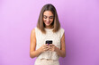 © luismolinero - Young caucasian woman isolated on purple background sending a message with the mobile