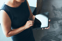 Businesswoman Working On Tablet In Office. Mature Woman Using Touch Pad Computer Standing By Window In Modern Interior. Manager Focused On Work Holding Digital Device. Using Technology