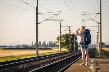 Wall Mural - Woman traveler with backpack waiting for train at railway station