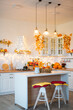 © sergiophoto - Autumn kitchen interior. Red and yellow leaves and flowers in the vase and pumpkin on light background