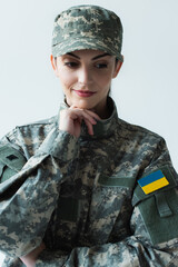 Portrait of pensive soldier in uniform with ukrainian flag isolated on grey