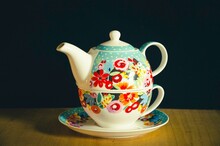 Close-up Of A Teapot And Cup With Beautiful Floral Pattern On A Black Background