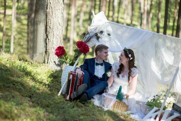 Wall Mural - View of groom and bride sitting and looking each other in park decorated for wedding