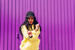 © Dani D.G - Positive young african american woman, dancing on purple wall.