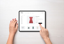 Online Shopping With A Tablet. Red Women's Dress On The E-commerce Web Page