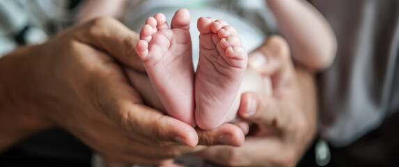 close-up detail of parent holding cute and soft baby small leg in his hands. macro abstract view of 