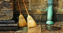 Closeup Shot Of Two Brooms Leaning On The Wall