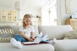 © VK Studio - Little european girl with book has leisure at cozy home. Preschool child is learning to read.