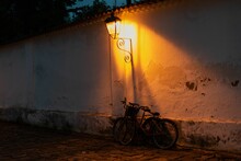 Beautiful Shot Of A Bicycle Under An Old Lantern Illuminating A Dark Street