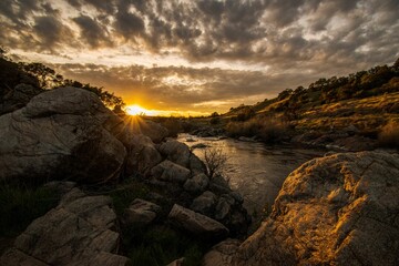 Sticker - Scenic view of rocky landscape with a small stream and beautiful sunset sky