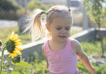 Canvas Print - little girl sniffing a sunflower.