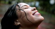 Happy young woman in rain shower outside, girl enjoying the rain outdoors, close-up face smiling