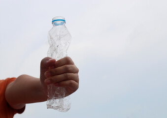  The concept of stop plastic, recycling. Woman hand holding a crumpled plastic bottle.