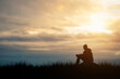 © Tarokmew - Silhouette of young man sits praying alone at the top of the mountain at sunset with beautiful natural sunlight.