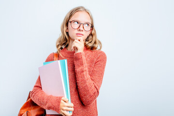 Caucasian teen student woman isolated on blue background looking sideways with doubtful and skeptical expression.