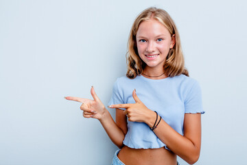 Caucasian teen girl isolated on blue background excited pointing with forefingers away.