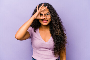 Wall Mural - Young hispanic woman isolated on purple background excited keeping ok gesture on eye.