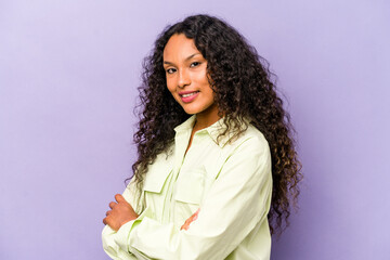 Wall Mural - Young hispanic woman isolated on purple background who feels confident, crossing arms with determination.