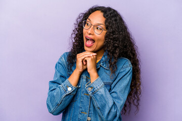 Wall Mural - Young hispanic woman isolated on purple background praying for luck, amazed and opening mouth looking to front.