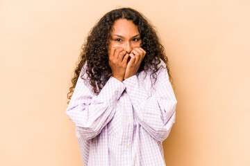 Wall Mural - Young hispanic woman isolated on beige background laughing about something, covering mouth with hands.