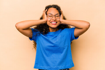 Wall Mural - Young hispanic woman isolated on beige background laughs joyfully keeping hands on head. Happiness concept.